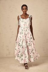 A long pink maxi dress with a floral print pattern and tied straps