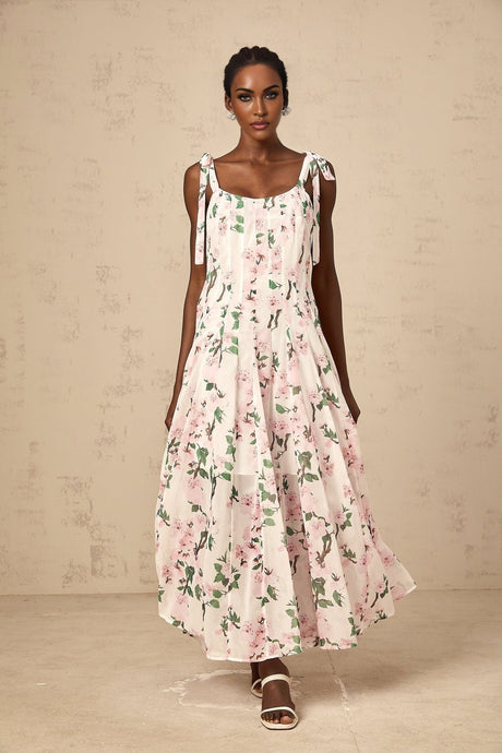 A long pink maxi dress with a floral print pattern and tied straps
