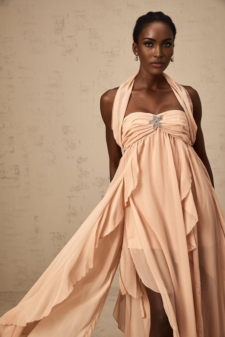 A long pink maxi dress with a halter neck and chiffon ruffles flowing down the body