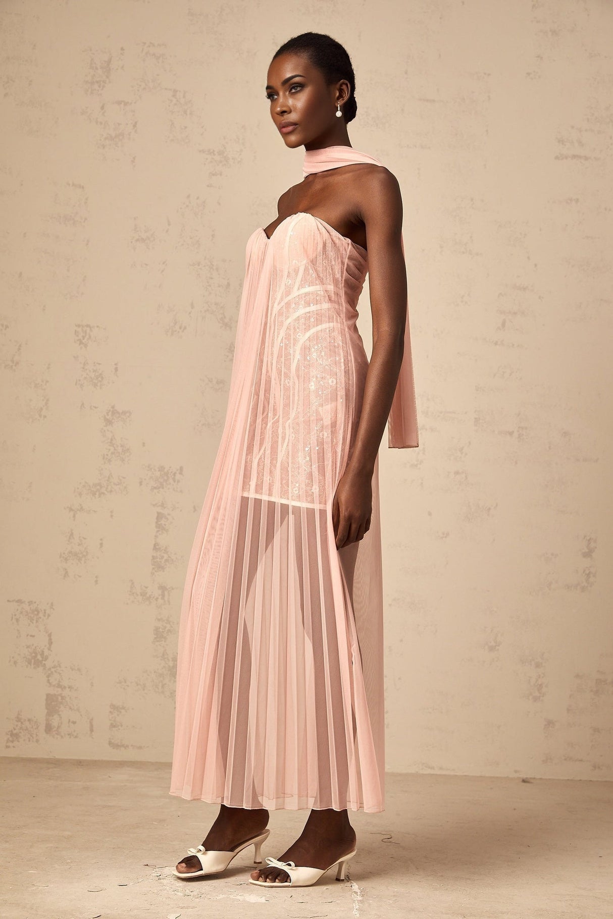 A long pink maxi dress with a pleated tulle skirt and ribbon design details on the bodice