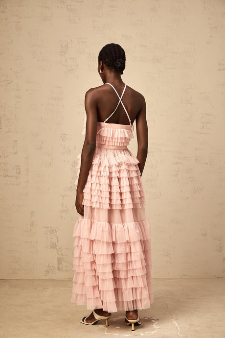 A long pink maxi dress with a tiered tulle skirt and ruffled details featuring a floral petal brooch at the waist named Isabelle