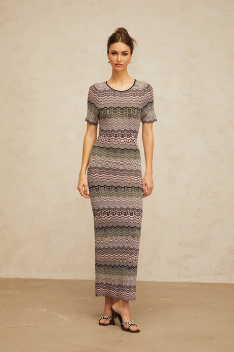 A long pink maxi dress with a wavy crochet knit pattern and a flowing silhouette