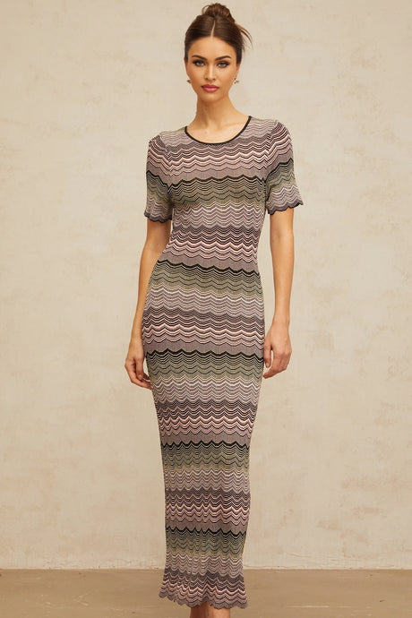 A long pink maxi dress with a wavy crochet knit pattern featuring a fitted bodice and flowing skirt