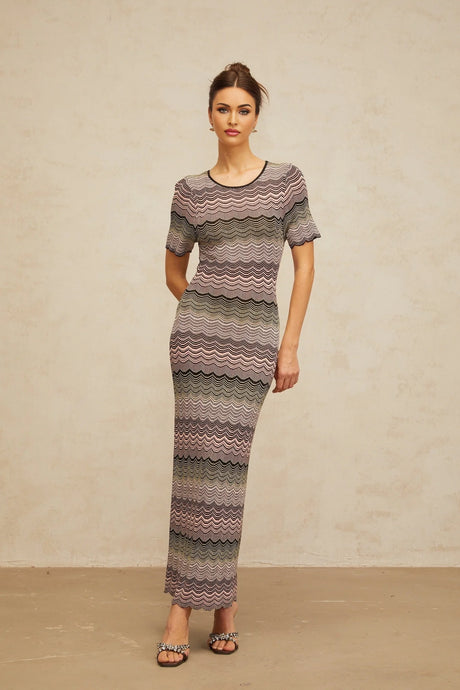 A long pink maxi dress with a wavy crochet knit pattern featuring a flowing skirt and fitted bodice