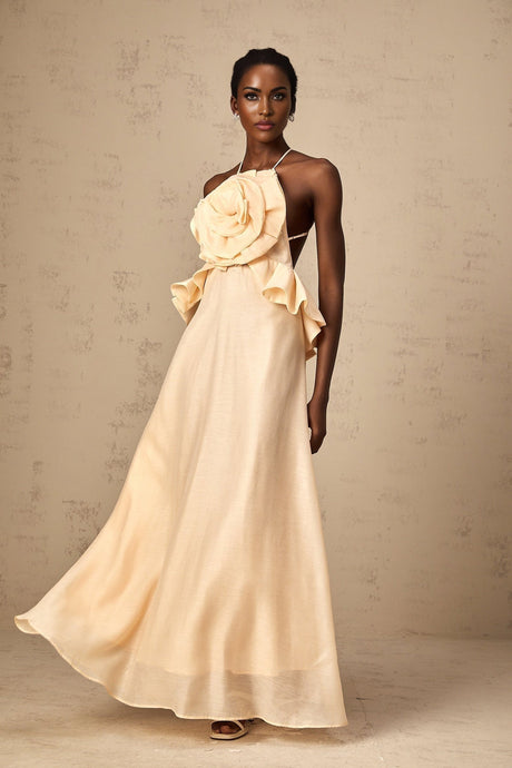 A long pink maxi dress with dramatic 3d petal ruffles covering the bodice and skirt creating a romantic floral effect