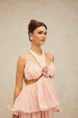 A long pink maxi dress with floral applique details and strategic cutouts featuring a feminine silhouette and flowing fabric