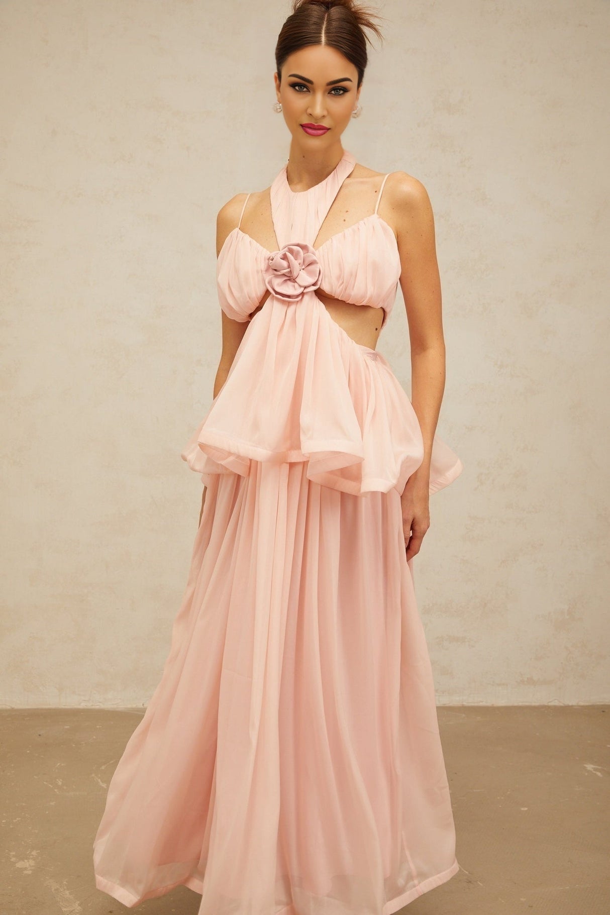 A long pink maxi dress with floral appliques and cutout details featuring a romantic and feminine design