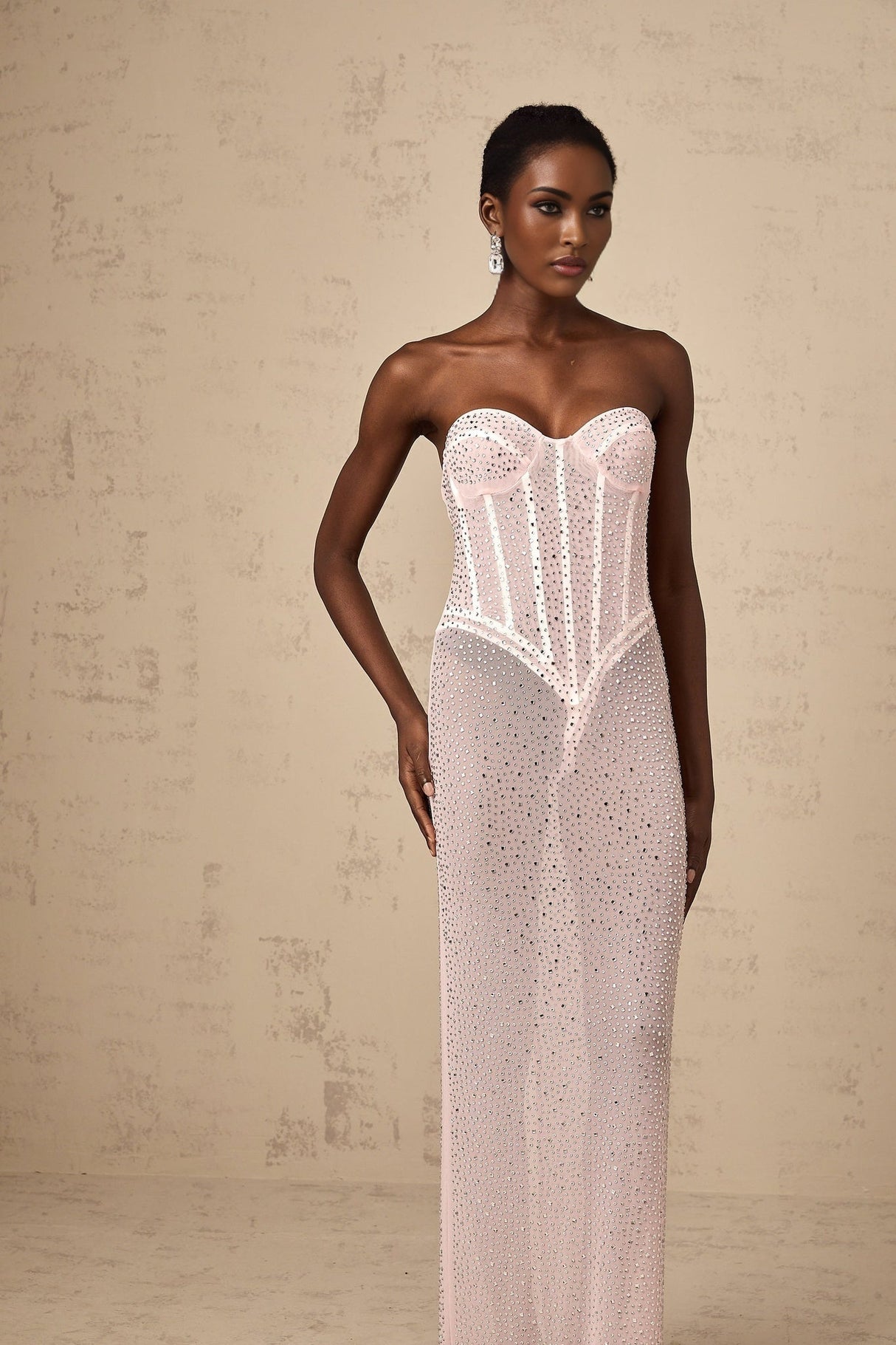 A long pink maxi dress with rhinestone embellishments and sheer elements featuring a flowing silhouette and delicate details