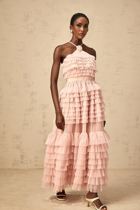 A long pink maxi dress with tiered ruffles and a tulle skirt featuring a large floral petal brooch at the waist