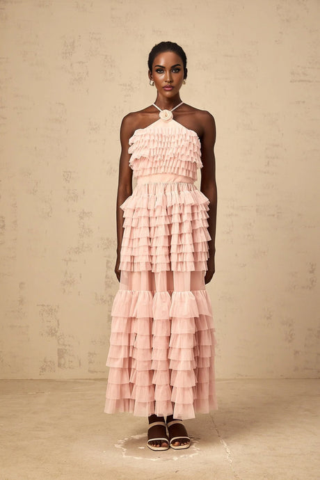 A long pink tiered tulle maxi dress with ruffles and a floral brooch accent at the waist