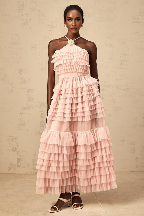 A long pink tulle maxi dress with tiered ruffles and a floral petal brooch accent featuring a feminine and romantic design