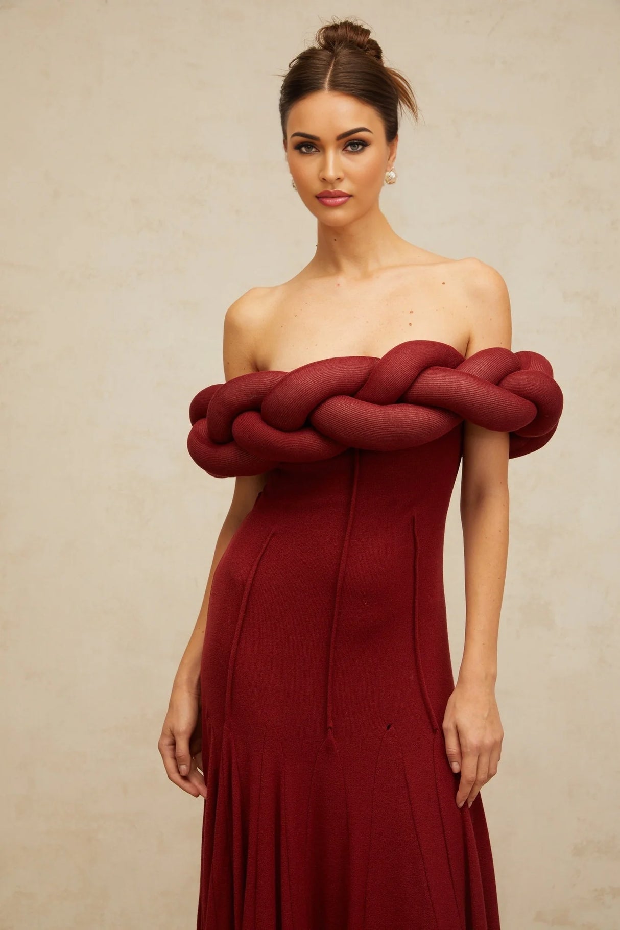 A long red knit maxi dress with a braided design pattern throughout featuring a form fitting silhouette and floor length hem