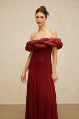 A long red knit maxi dress with a braided design pattern worn by a female model