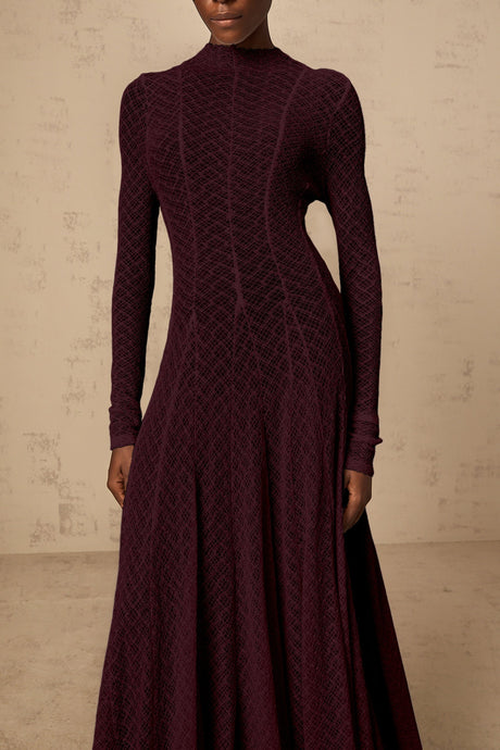 A long red maxi dress with a wavy lace pattern covering the entire garment The dress features a feminine silhouette and delicate detailing