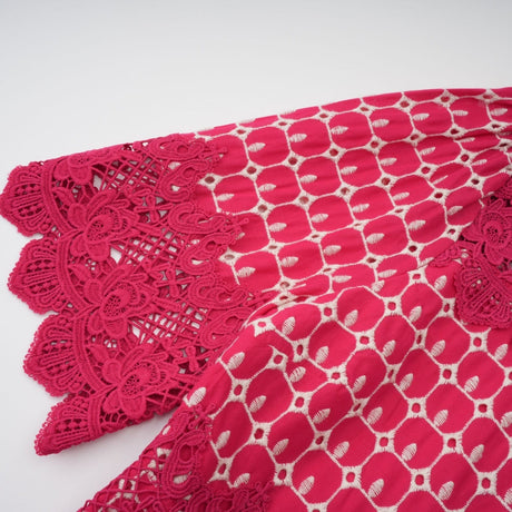 A long red maxi dress with scalloped lace panels featuring a delicate pattern throughout the design