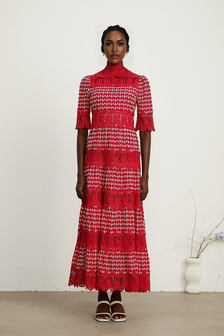 A long red maxi dress with scalloped lace panels featuring a delicate pattern throughout the garment