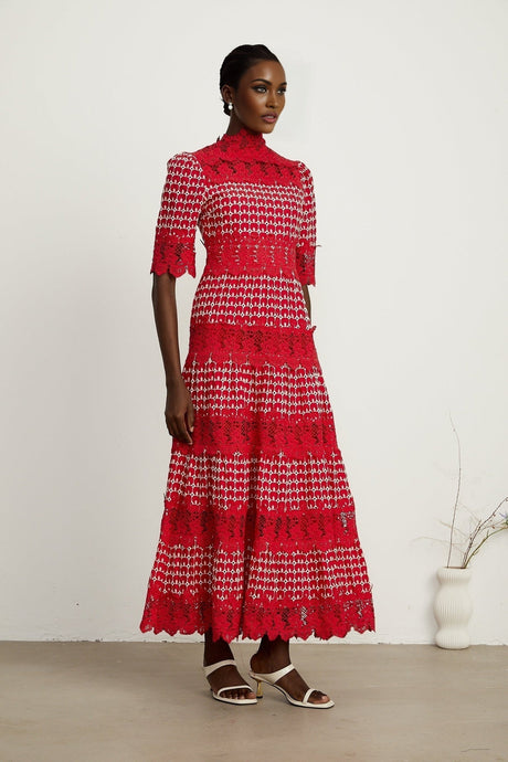 A long red maxi dress with scalloped lace panels featuring a floral pattern The dress has a fitted bodice and flowing skirt creating an elegant silhouette