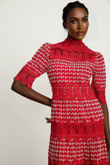 A long red maxi dress with scalloped lace panels featuring a floral pattern The dress has a fitted bodice and flowing skirt with a feminine silhouette