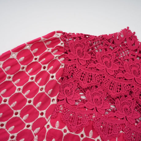 A long red maxi dress with scalloped lace panels featuring a floral pattern The dress has a fitted bodice and flows into a full length skirt