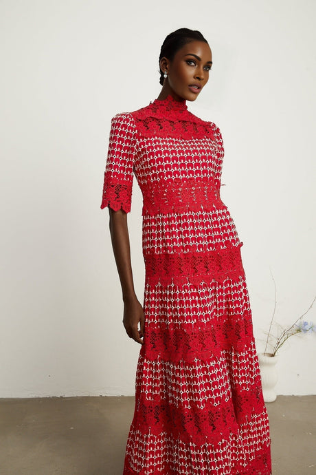 A long red maxi dress with scalloped lace panels featuring a floral pattern The dress has a fitted bodice and flowy skirt