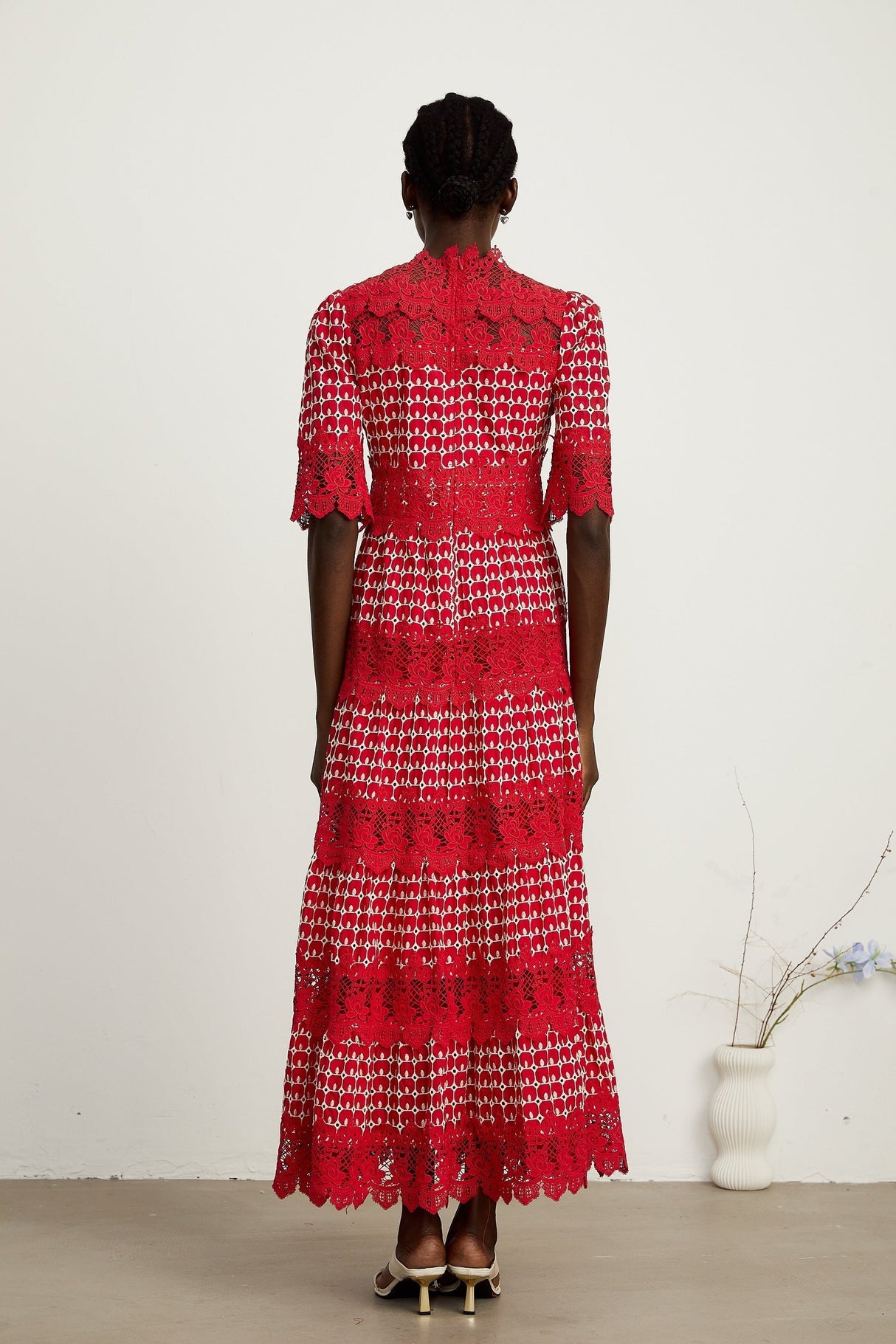A long red maxi dress with scalloped lace panels featuring a floral pattern