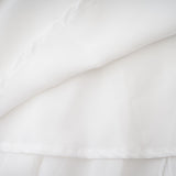 A long white chiffon maxi dress with a halter neck and ruffle details worn by a model against a plain background