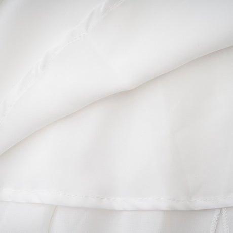 A long white chiffon maxi dress with a halter neck and ruffle details worn by a model against a plain background