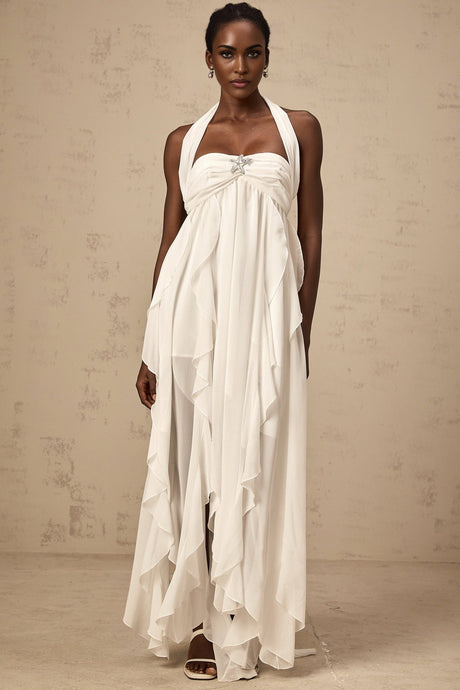 A long white chiffon maxi dress with ruffle details and a halter neckline worn by a model against a plain background