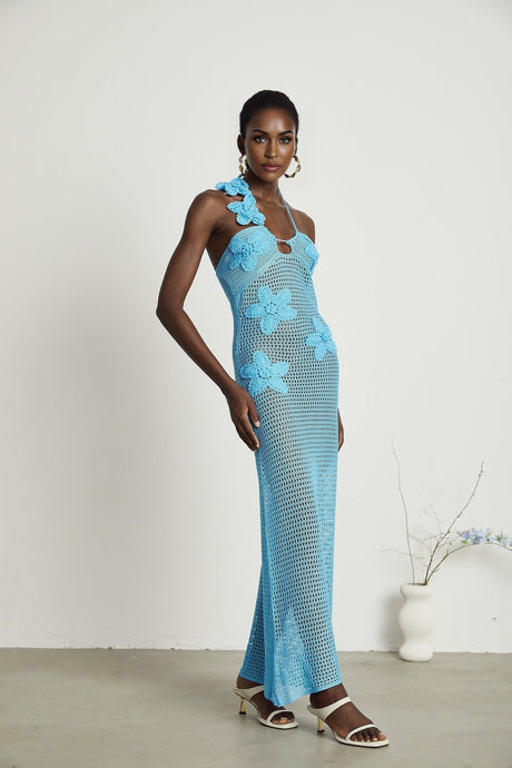 A long white crochet maxi dress with colorful faux flower embellishments scattered throughout the design