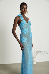 A long white crochet maxi dress with colorful faux flower embellishments scattered throughout the design