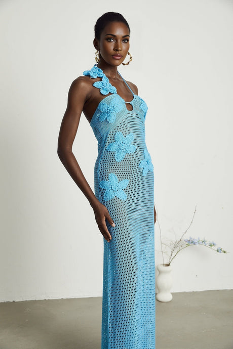 A long white crochet maxi dress with colorful faux flower embellishments scattered throughout the design