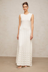 A long white knit maxi dress with a pointelle pattern and faux pearl embellishments