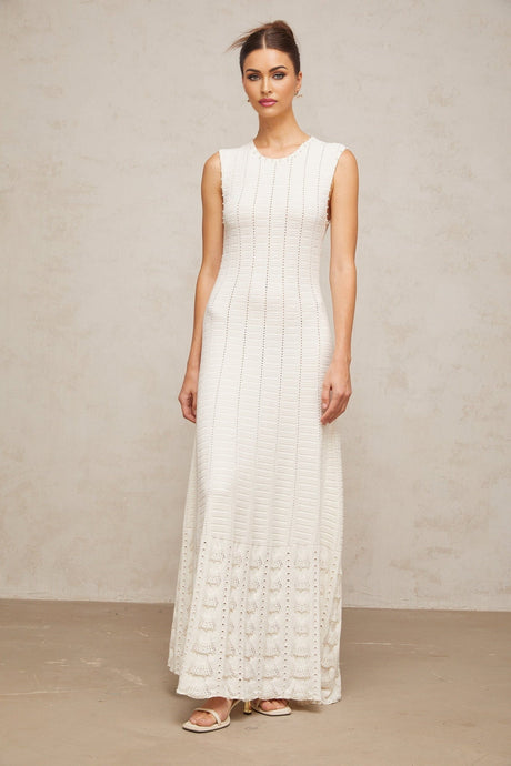 A long white knit maxi dress with a pointelle pattern and faux pearl embellishments