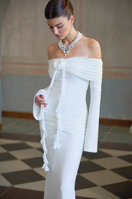 A long white knit maxi dress with glittered floral appliques named Wanda shown on a model against a plain background