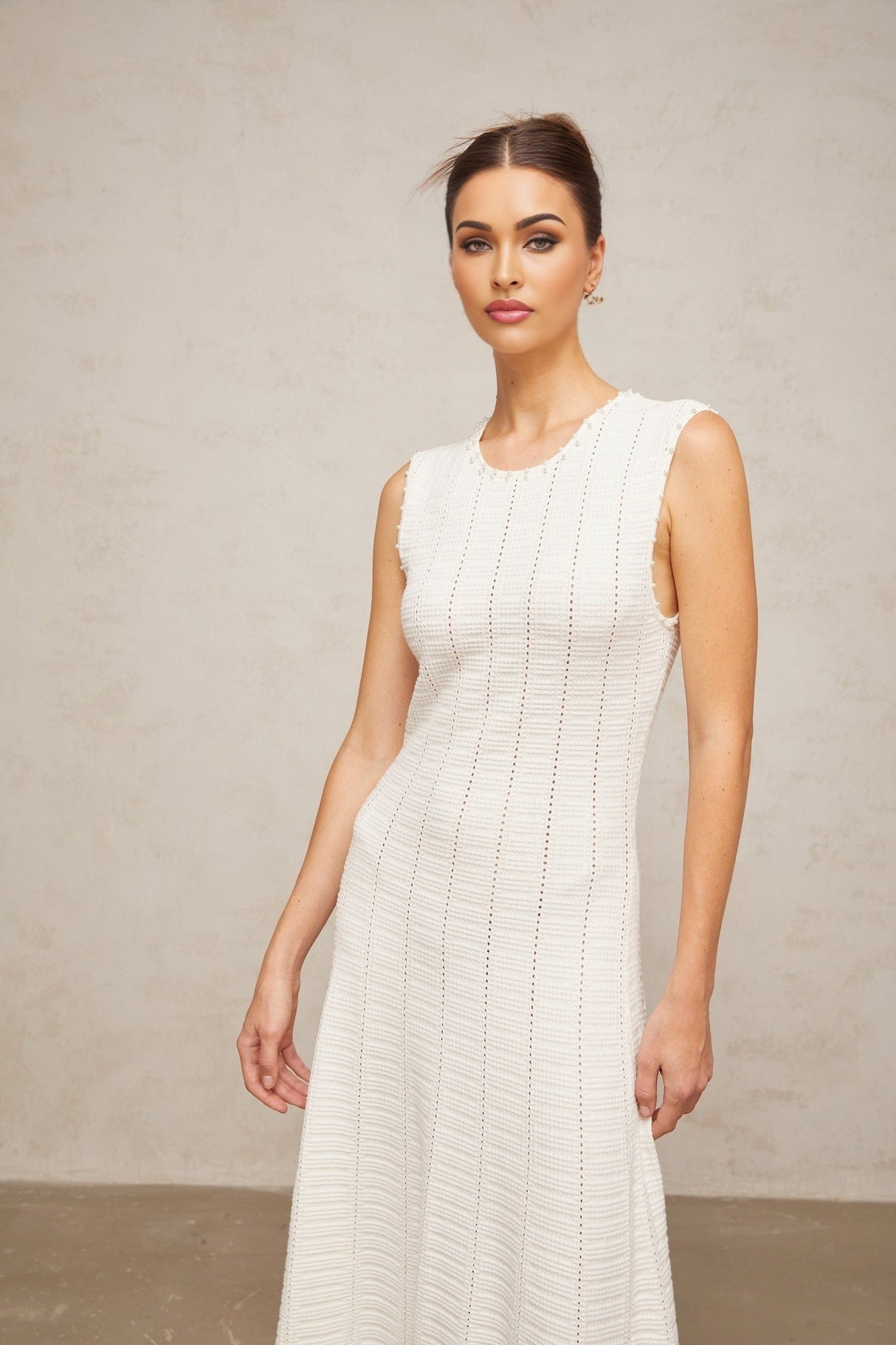 A long white knit maxi dress with pointelle detailing and faux pearl embellishments