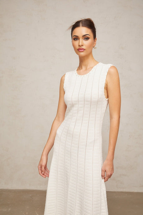 A long white knit maxi dress with pointelle detailing and faux pearl embellishments