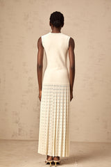 A long white knitted maxi dress with faux pearl embellishments throughout the fabric
