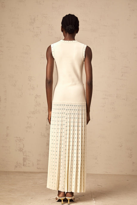 A long white knitted maxi dress with faux pearl embellishments throughout the fabric