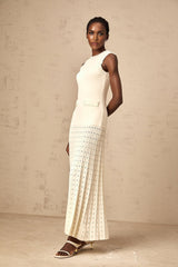 A long white knitted maxi dress with faux pearl embellishments throughout the fabric