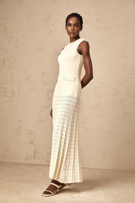 A long white knitted maxi dress with faux pearl embellishments throughout the fabric