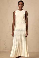 A long white knitted maxi dress with faux pearl embellishments throughout the fabric