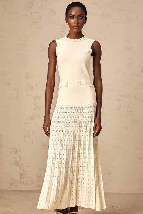 A long white knitted maxi dress with faux pearl embellishments throughout the fabric