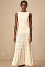 A long white knitted maxi dress with faux pearl embellishments throughout the fabric