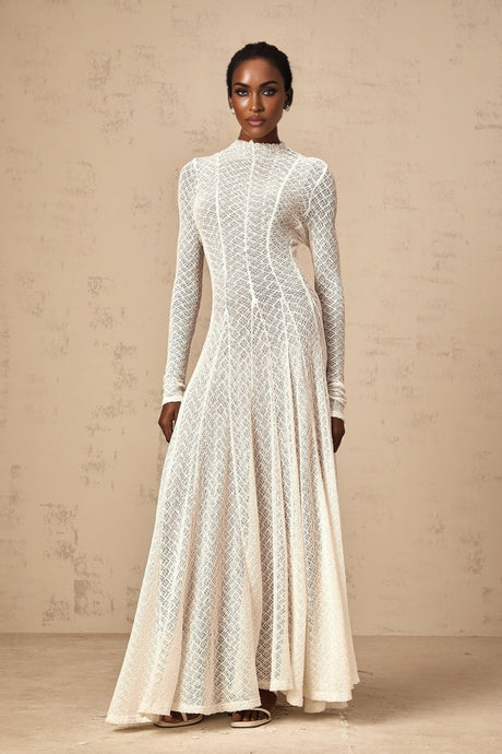 A long white lace maxi dress with a wavy pattern design featuring a flowy silhouette and delicate lace details throughout