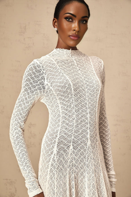 A long white lace maxi dress with a wavy pattern design featuring intricate details and a flowing silhouette
