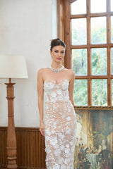 A long white maxi dress with a corset bodice adorned with floral applique detailing named Brigitte