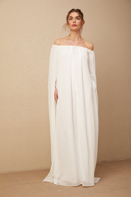 A long white maxi dress with a flowing tulle skirt and capelike draped design on the upper body