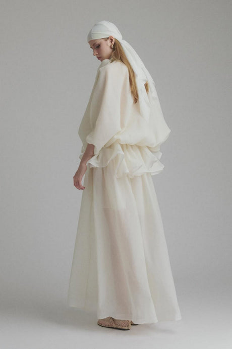 A long white maxi dress with a tie neck and ruffled details