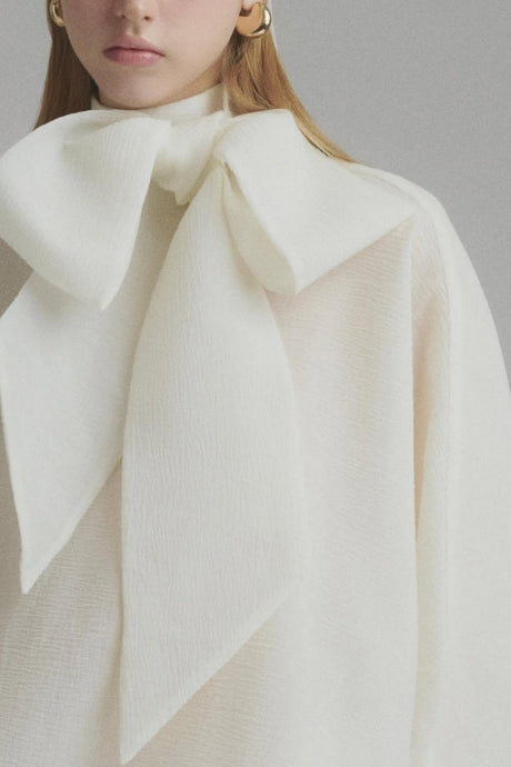 A long white maxi dress with a tie neck and ruffled details