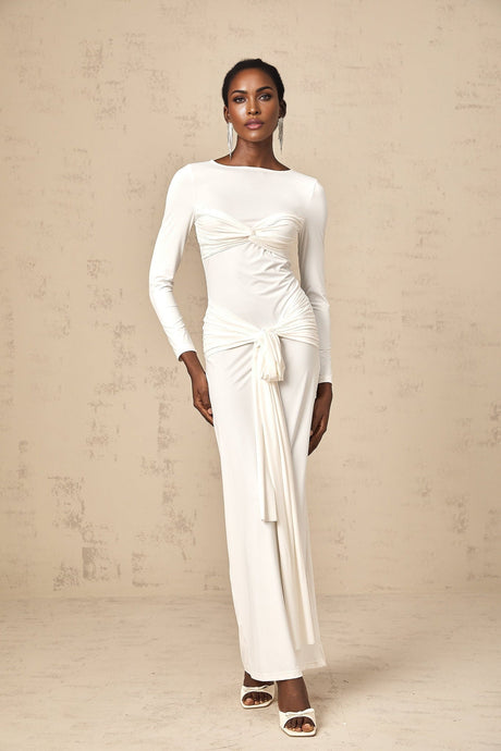 A long white maxi dress with ruched fabric featuring a twist detail and ribbon accents